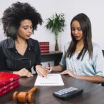 african american woman pointing document near lady with pen table(1)